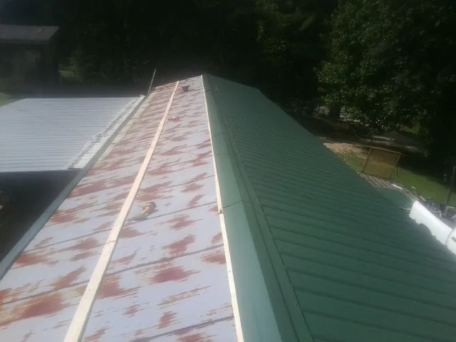 Old rusted panels beside newly installed green metal roofing — Wind Damage Roof Repair by Roofing Brothers in Sargent
