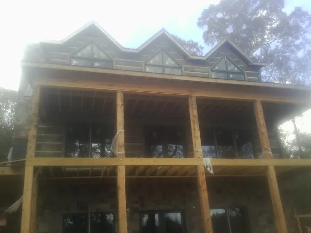 Dormers and porch framing on a large log home under construction — Roof Coating work by our crew in Sargent