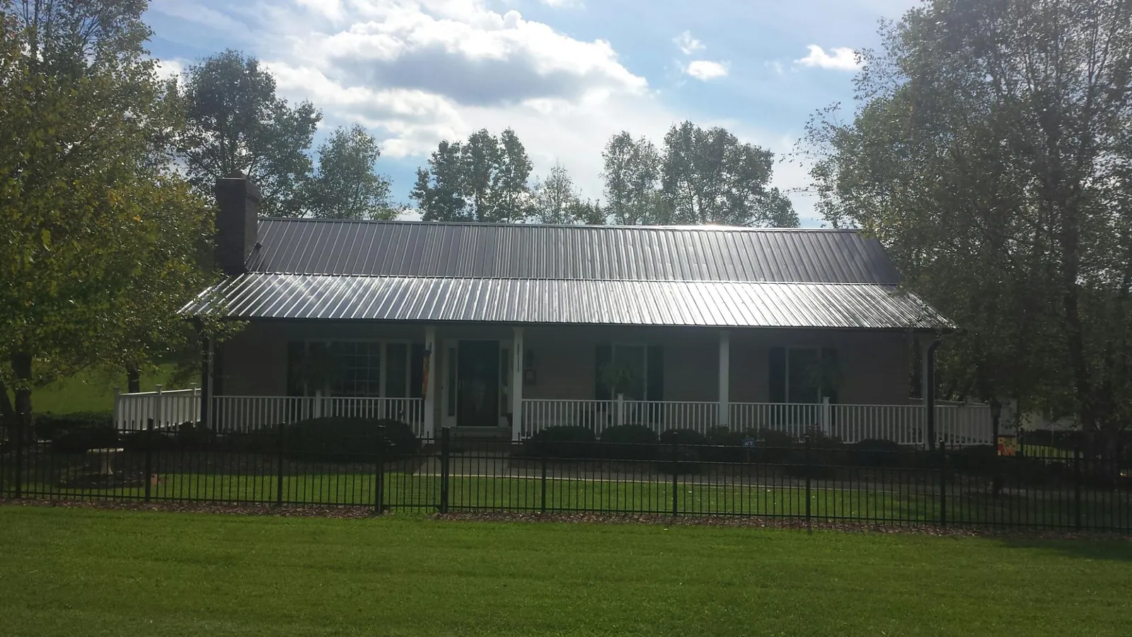 Gray metal roof on a brick ranch with a full width front porch — Gutter Guard Installation work by our crew in Sargent