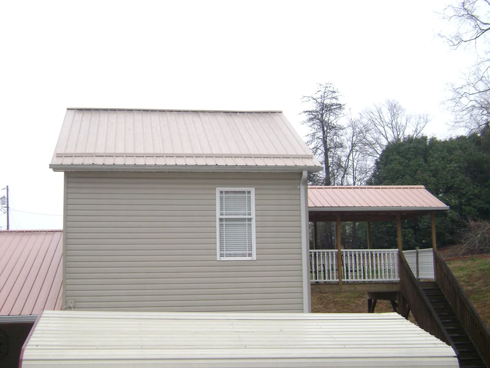Tan metal roofs on a two story addition and attached porch, from a Roof Replacement job in Sargent